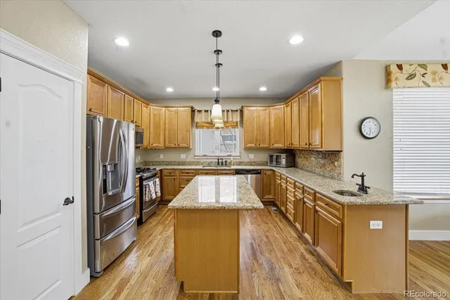 a kitchen with stainless steel appliances granite countertop a sink a refrigerator and a stove