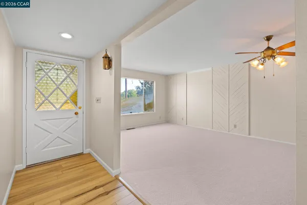 a view of empty room with wooden floor and fan