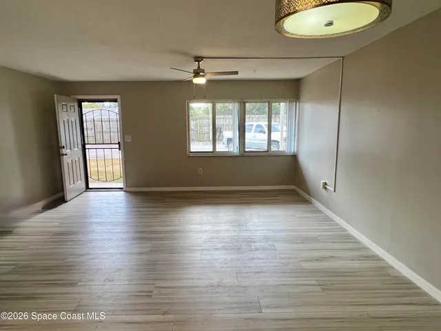 an empty room with wooden floor and windows