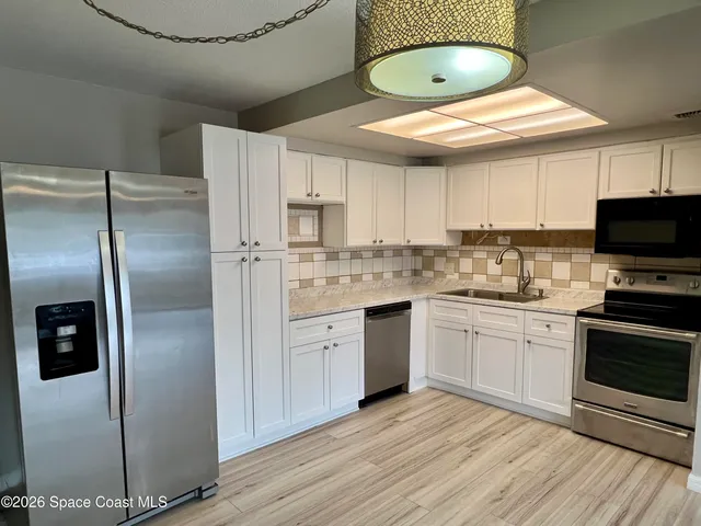 a kitchen with stainless steel appliances a refrigerator a stove a sink and white cabinets