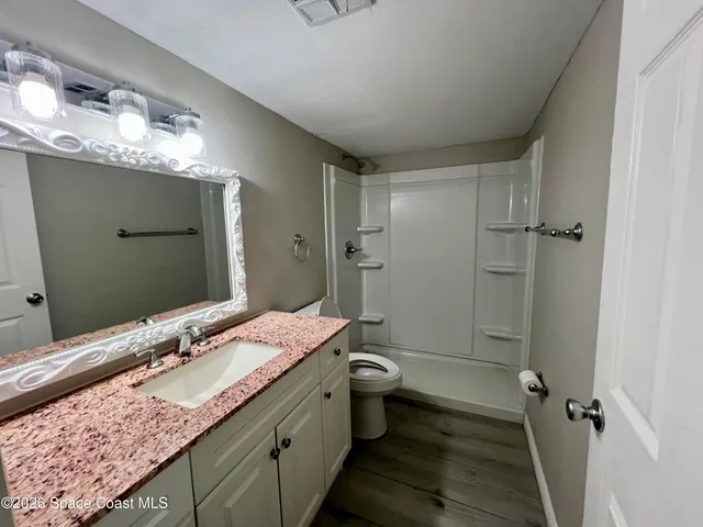 a bathroom with a granite countertop sink a toilet and shower