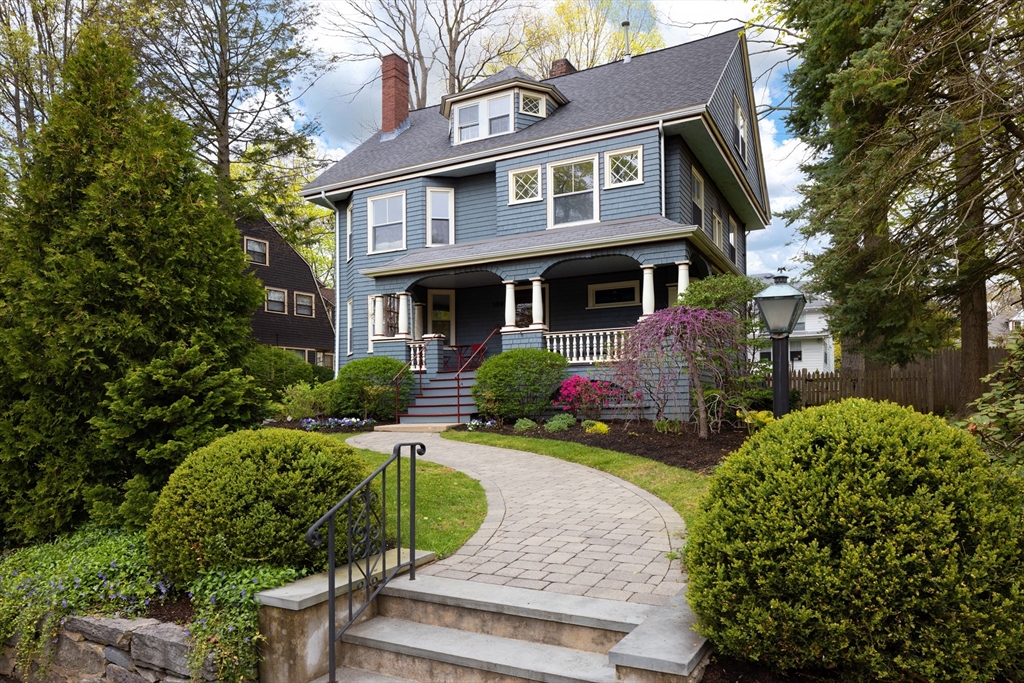 a view of a brick house with a yard plants and a lawn chair