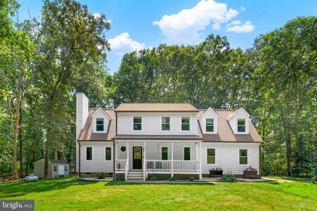 a view of a large white building next to a yard with large trees