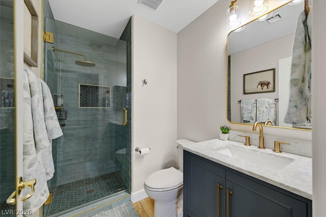 1259 Moon Vision Street Henderson, NV 89052 - Photo 32 of 53 A well-appointed bathroom features a glass-enclosed shower with a rainfall showerhead and a vanity with a white marble countertop.