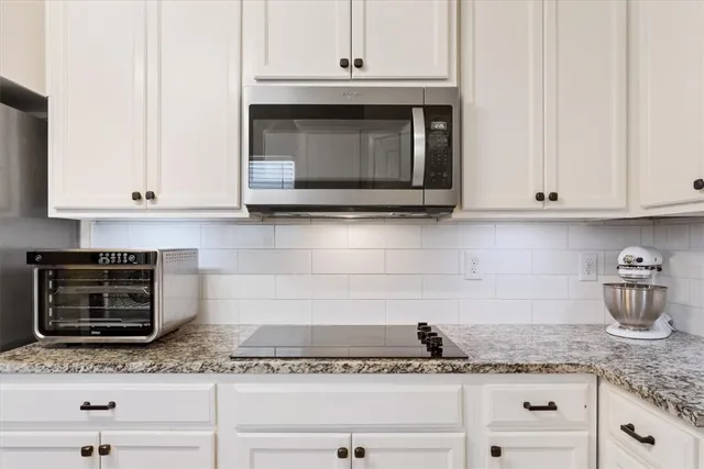 a kitchen with granite countertop white cabinets and a stove