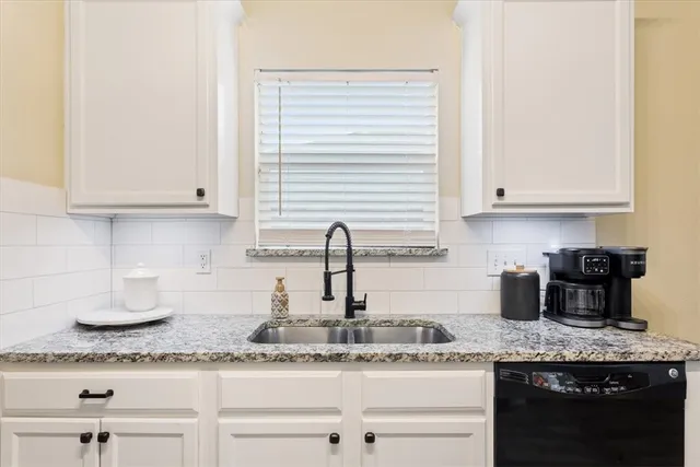 a kitchen with granite countertop white cabinets and a sink