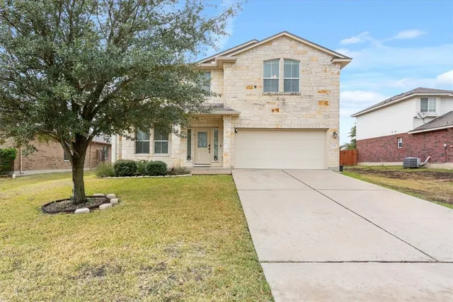 a view of a yard in front of a house with a tree