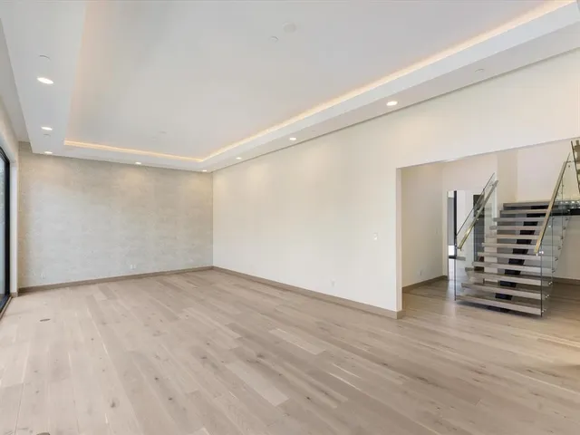 a view of an empty room with wooden floor and stairs