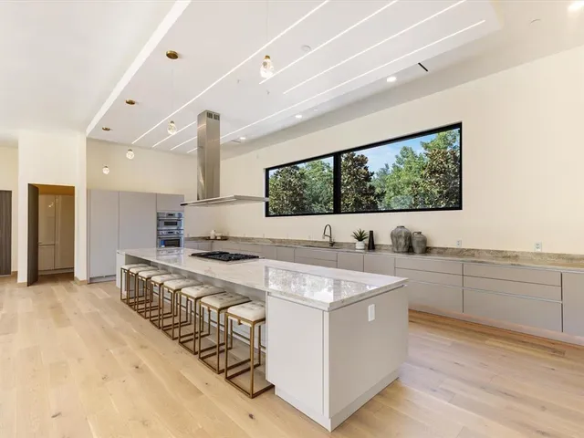 a large white kitchen with a stove a sink dishwasher and white cabinets with wooden floor