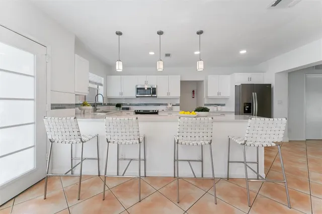 a kitchen with stainless steel appliances kitchen island granite countertop a refrigerator and cabinets