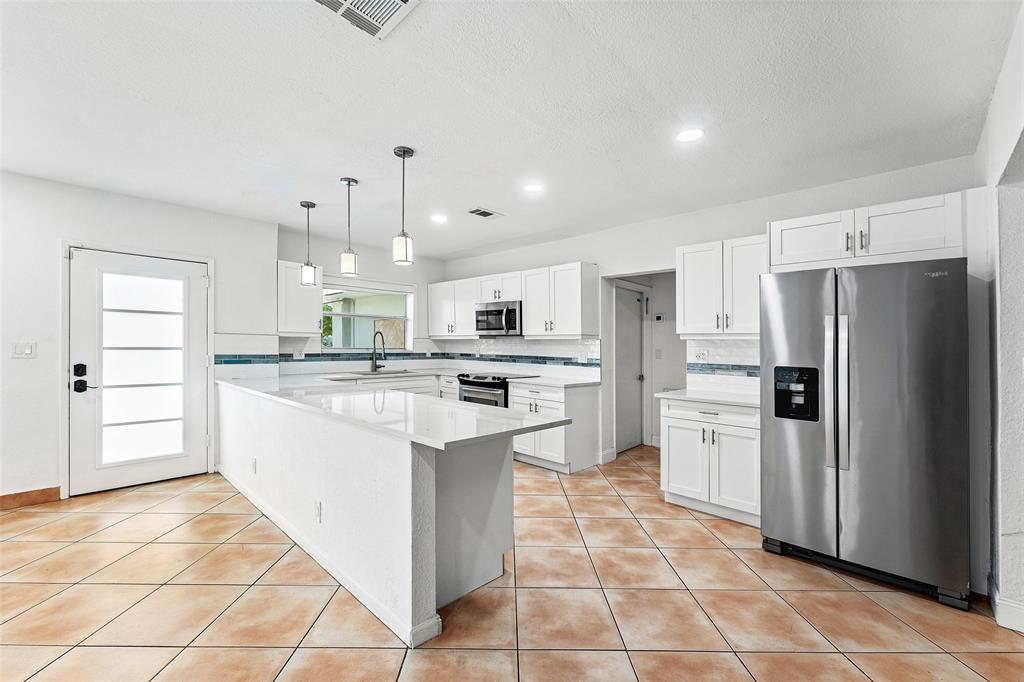 3203 Dover Road Pompano Beach, FL 33062 - Photo 9 of 54 a kitchen with stainless steel appliances kitchen island granite countertop a refrigerator and a stove top oven