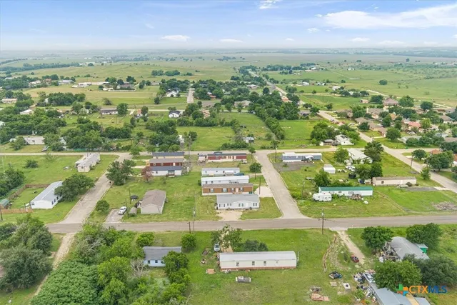 an aerial view of residential houses with outdoor space and trees