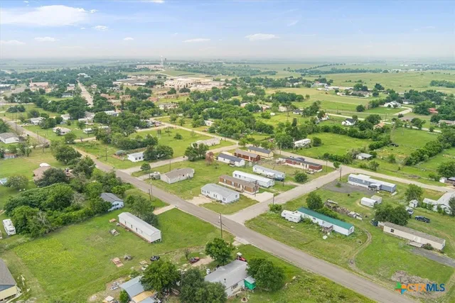 an aerial view of residential houses with outdoor space and trees