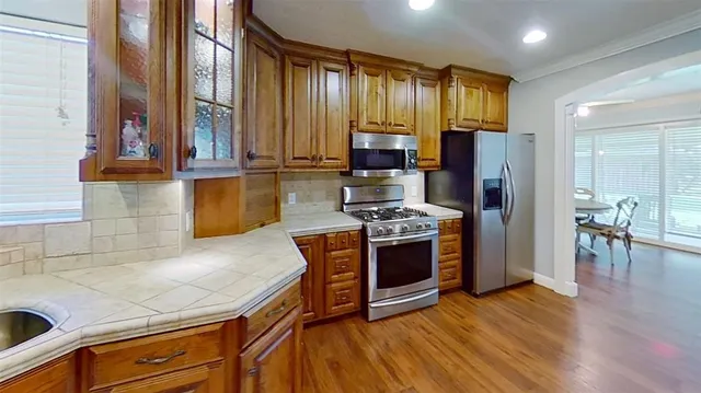 a kitchen with stainless steel appliances granite countertop a stove a refrigerator and a microwave oven with large wooden cabinets