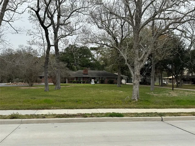 a view of a house with a big yard and large trees