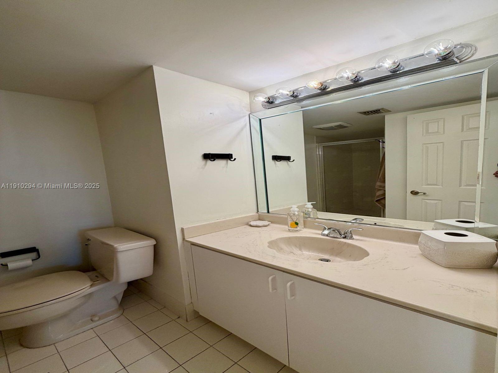 6061 Collins Avenue, Unit 11A Miami Beach, FL 33140 - Photo 23 of 30 a bathroom with a granite countertop sink a toilet and mirror