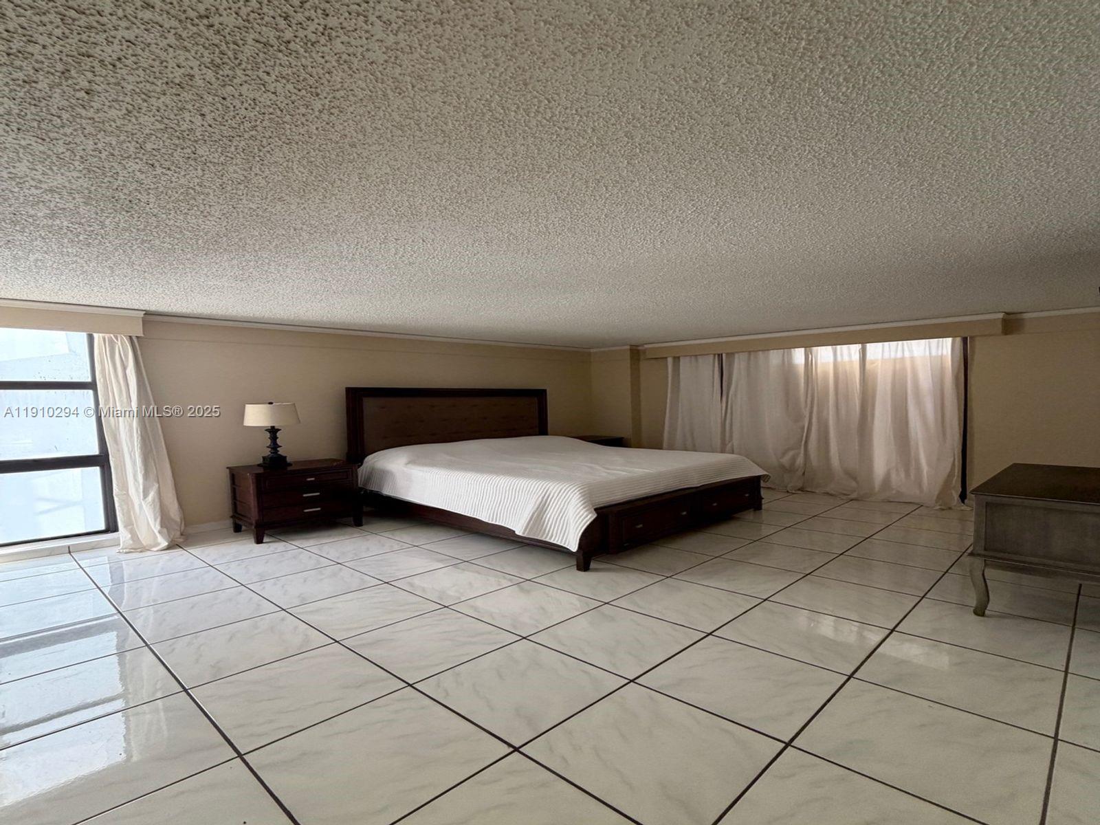 6061 Collins Avenue, Unit 11A Miami Beach, FL 33140 - Photo 25 of 30 a spacious bedroom with a bed and a cabinets