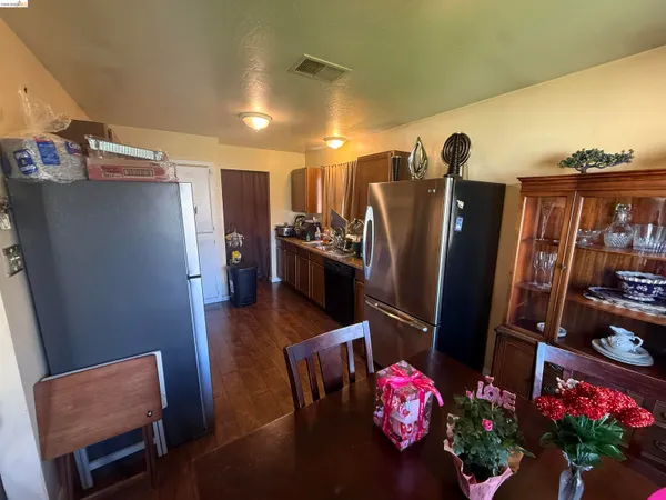a kitchen with stainless steel appliances kitchen island granite countertop a refrigerator a stove and a dining table with wooden floor