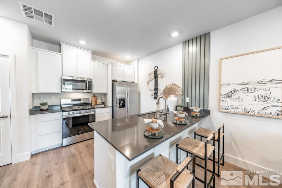 1605 Switchback Street, Unit LOT #29 Reno, NV 89523 - Photo 6 of 20 a kitchen with stainless steel appliances kitchen island granite countertop a stove a refrigerator a kitchen island a table and chairs with wooden floor