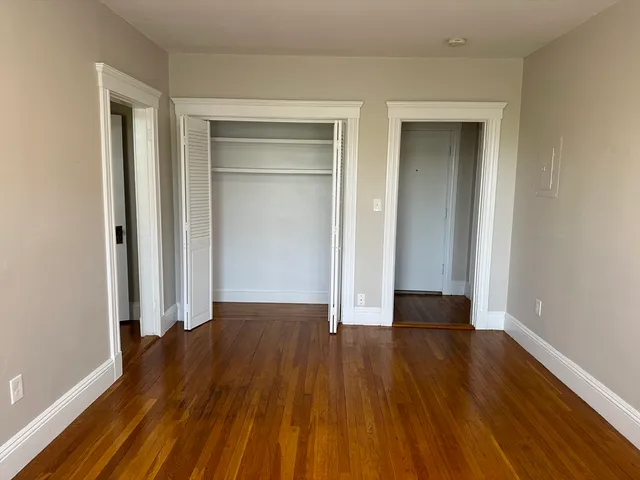 a view of empty room with wooden floor and closet