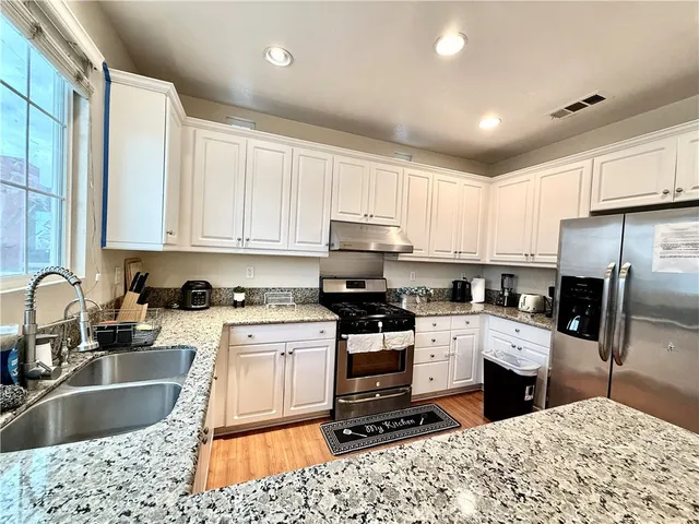 a kitchen with stainless steel appliances kitchen island granite countertop a sink stove and refrigerator