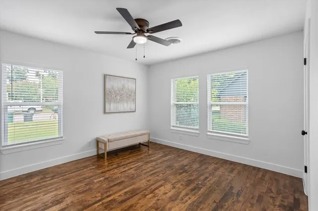 a view of an empty room with a window and wooden floor