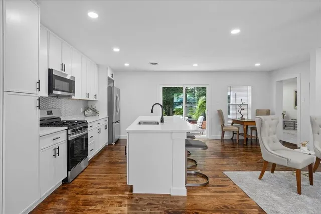 a living room with stainless steel appliances furniture and a kitchen view