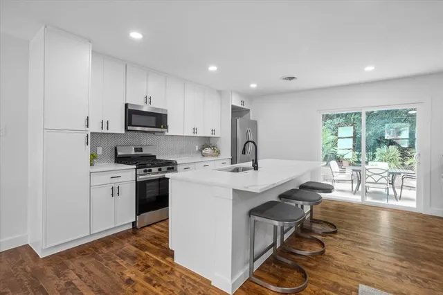 a kitchen with stainless steel appliances a sink a stove a refrigerator cabinets and a dining table