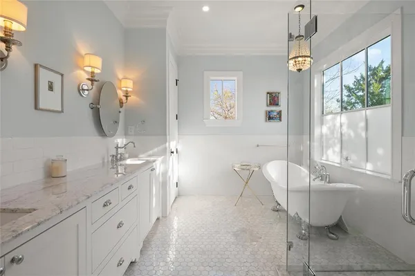 a spacious bathroom with a double vanity sink a large mirror a bathtub and next to a window