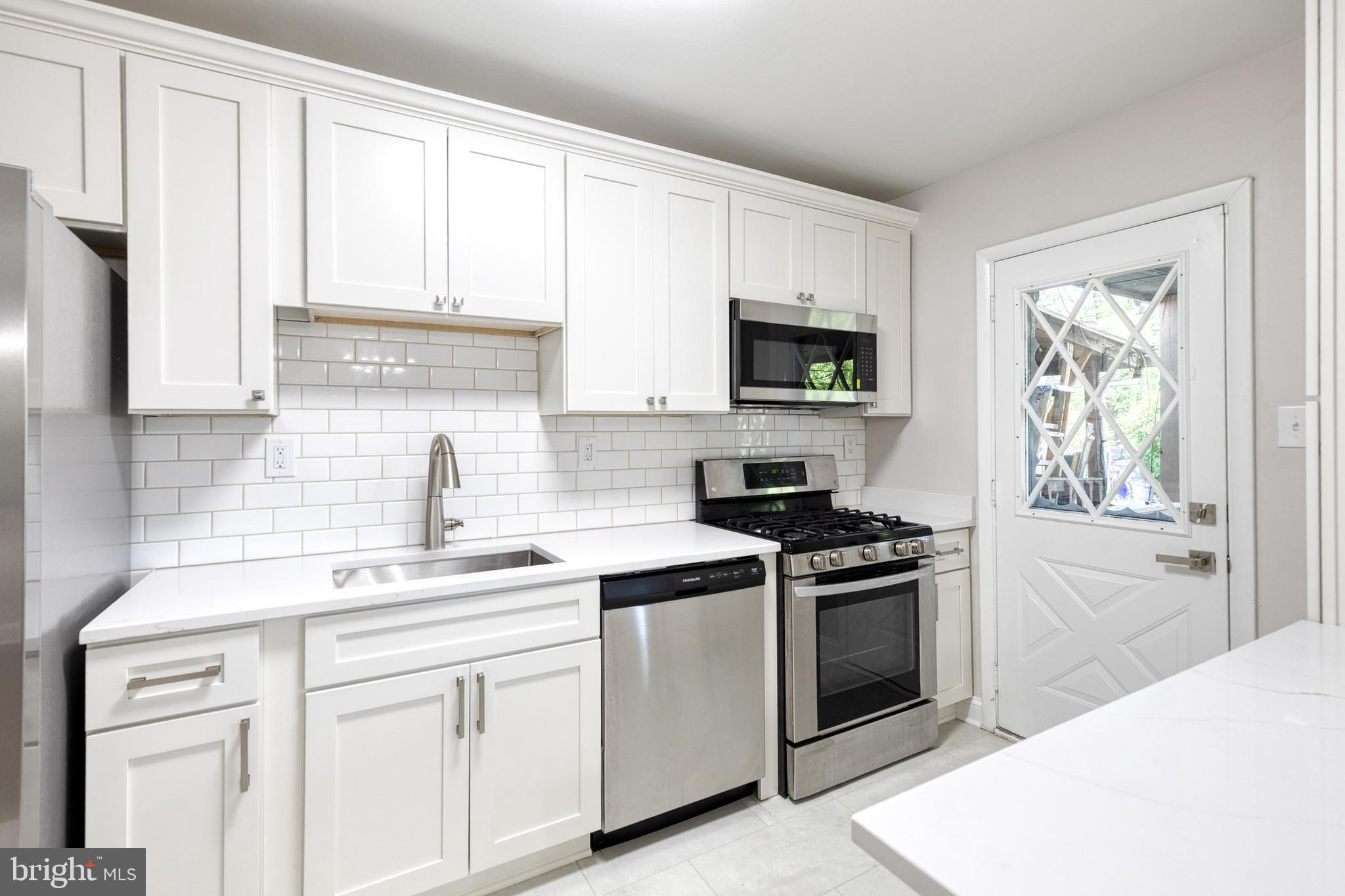 5649 Utrecht Road Baltimore, MD 21206 - Photo 11 of 42 a kitchen with cabinets stainless steel appliances a sink and a window