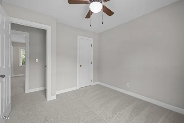 an empty room with a chandelier fan and closet