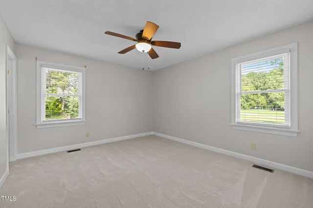 an empty room with windows and fan