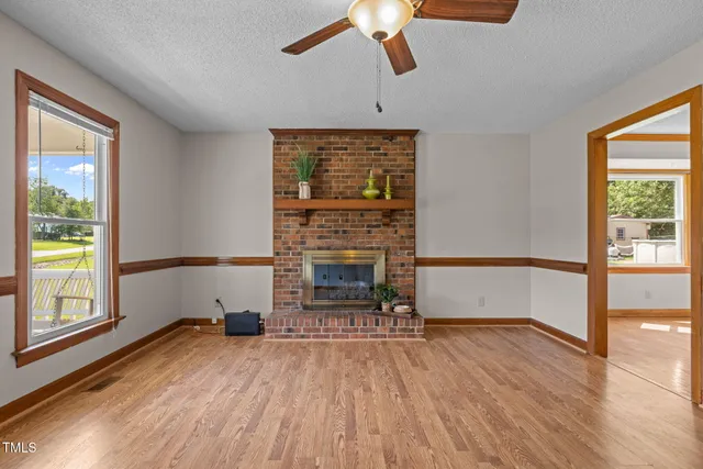 an empty room with fireplace wooden floor and windows