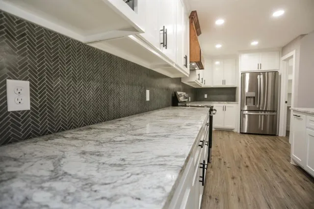 a large white kitchen with kitchen island granite countertop a sink and cabinets