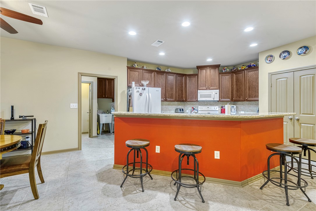 9945 Oxford Cemetery Road Madisonville, TX 77864 - Photo 11 of 42 Kitchen featuring decorative backsplash, recessed lighting, white appliances, a kitchen breakfast bar, and light stone countertops