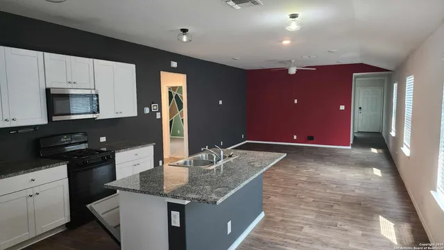 a kitchen with kitchen island granite countertop a sink and cabinets