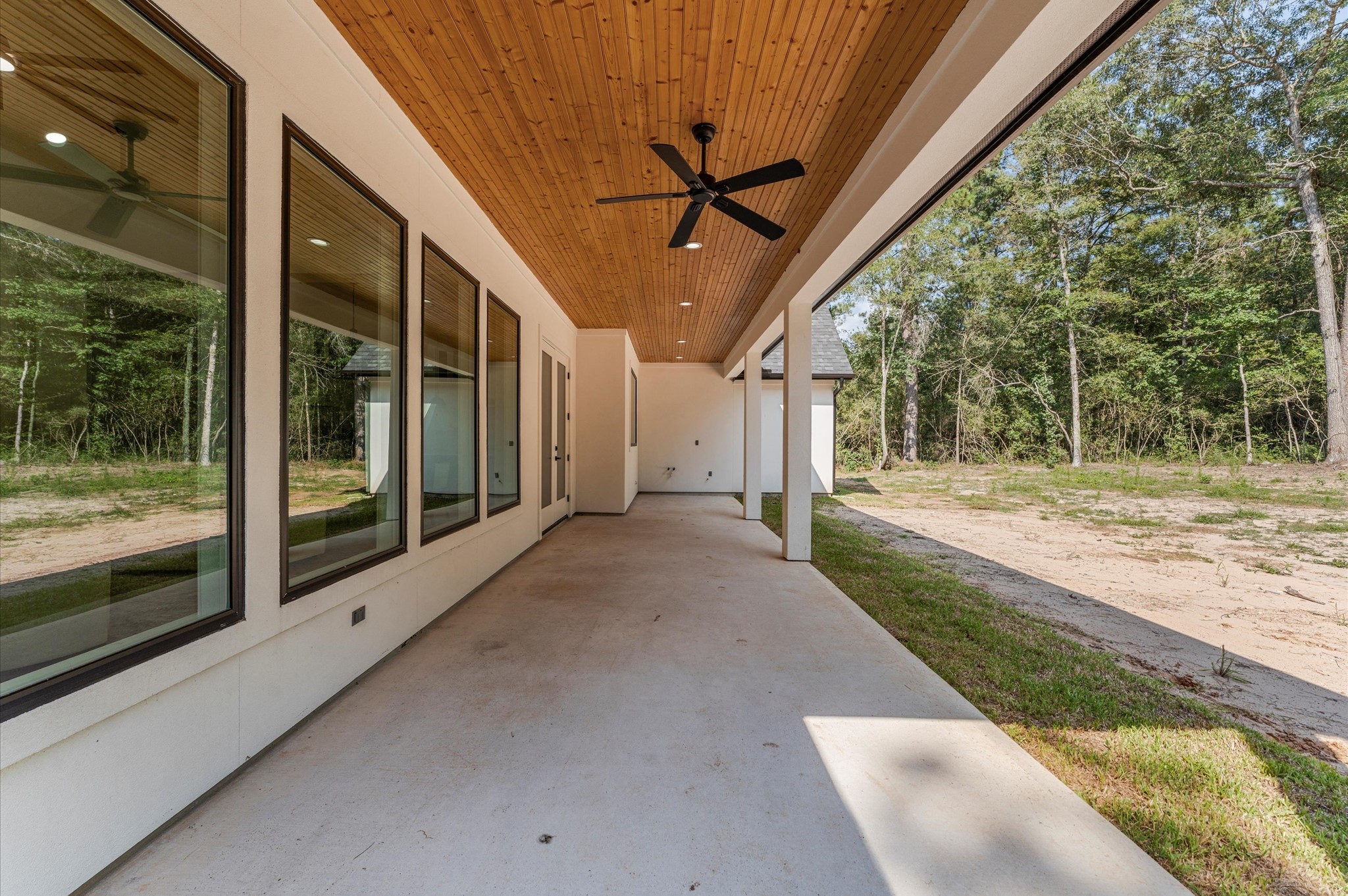 118 Ranger Road Huntsville, TX 77340 - Photo 44 of 49 Covered back porch with wood-accent ceiling and LED lights, offering peaceful views of the expansive backyard.