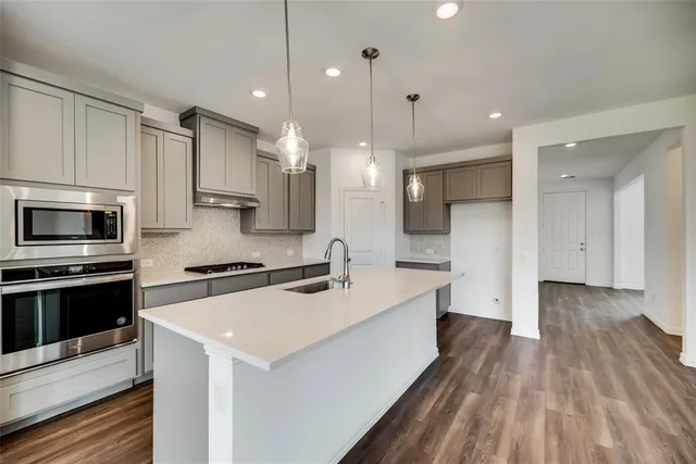 a large kitchen with stainless steel appliances a large counter top a stove a refrigerator and a sink