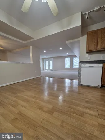 a view of an empty room with kitchen and a window