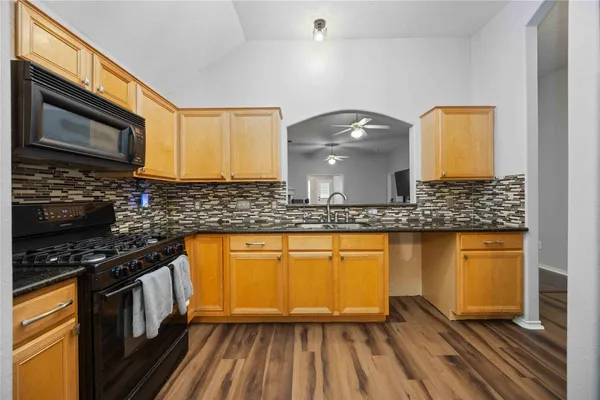 a kitchen with stainless steel appliances granite countertop a stove a sink and a microwave