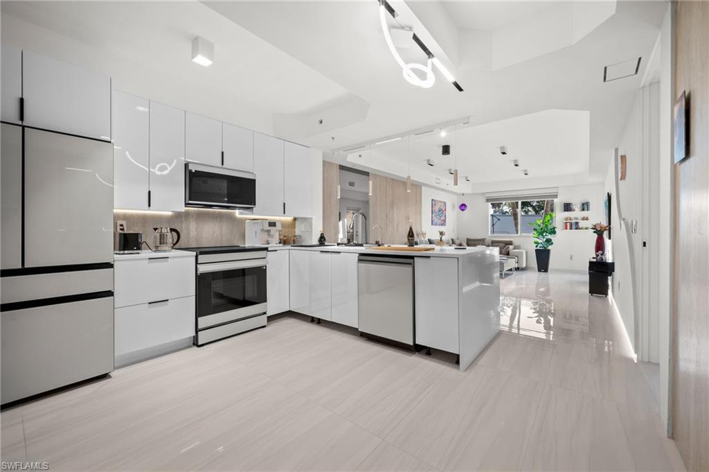 1100 Pine Ridge Road, Unit B103 Naples, FL 34108 - Photo 11 of 38 a kitchen with white cabinets and stainless steel appliances