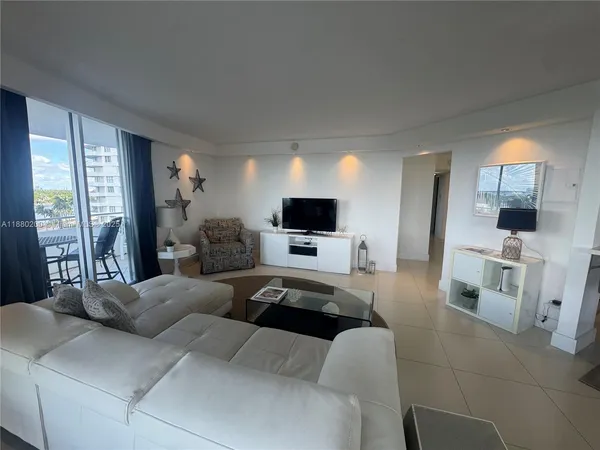 a living room with furniture a flat screen tv and a large window