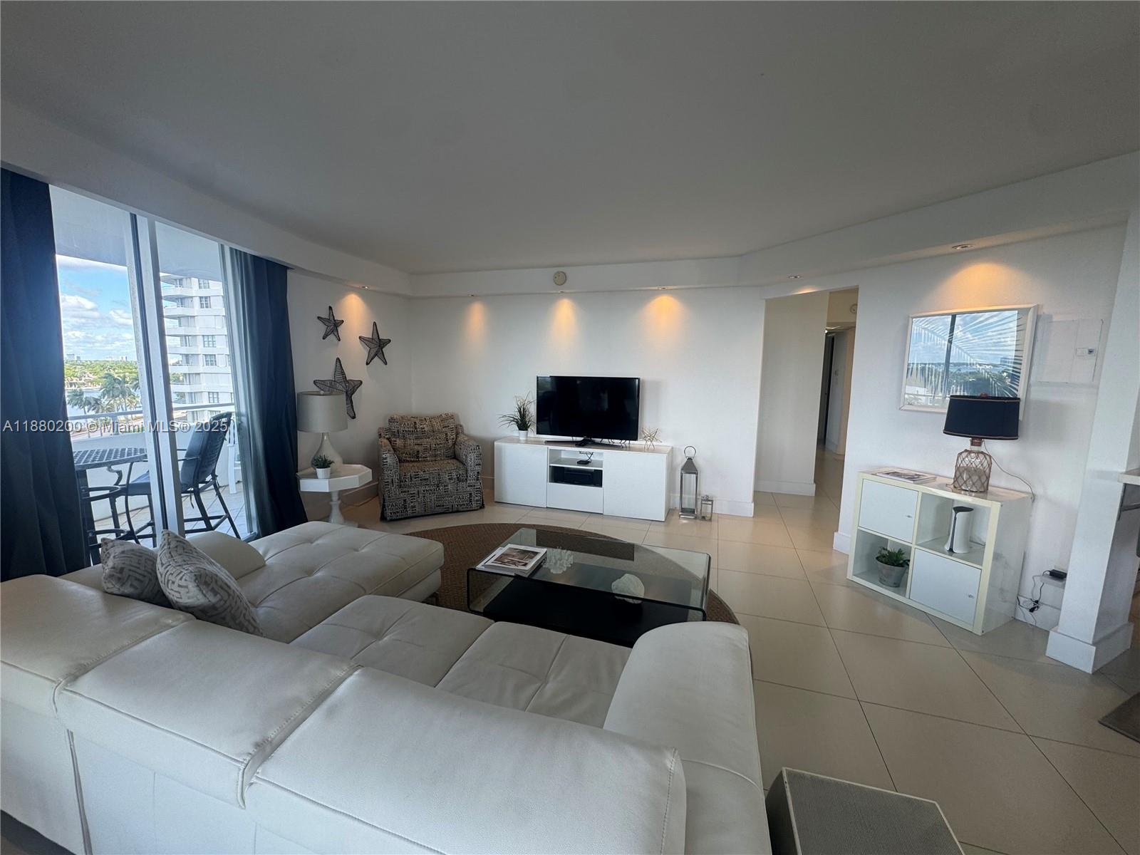 5151 Collins Avenue, Unit 923 Miami Beach, FL 33140 - Photo 2 of 32 a living room with furniture a flat screen tv and a large window