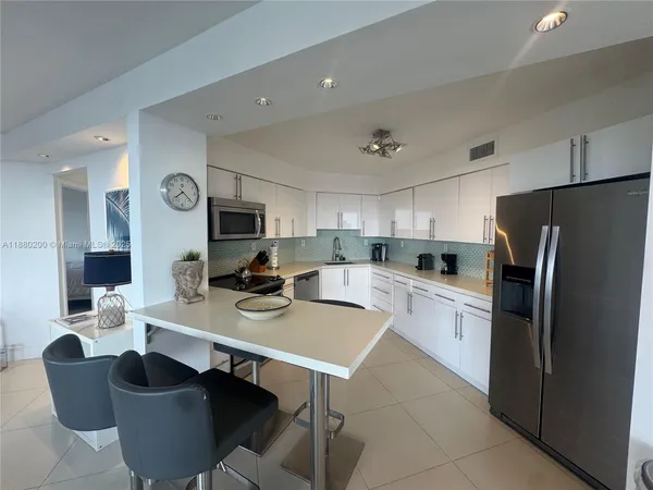 a kitchen with stainless steel appliances granite countertop a stove a refrigerator a sink a dining table and chairs