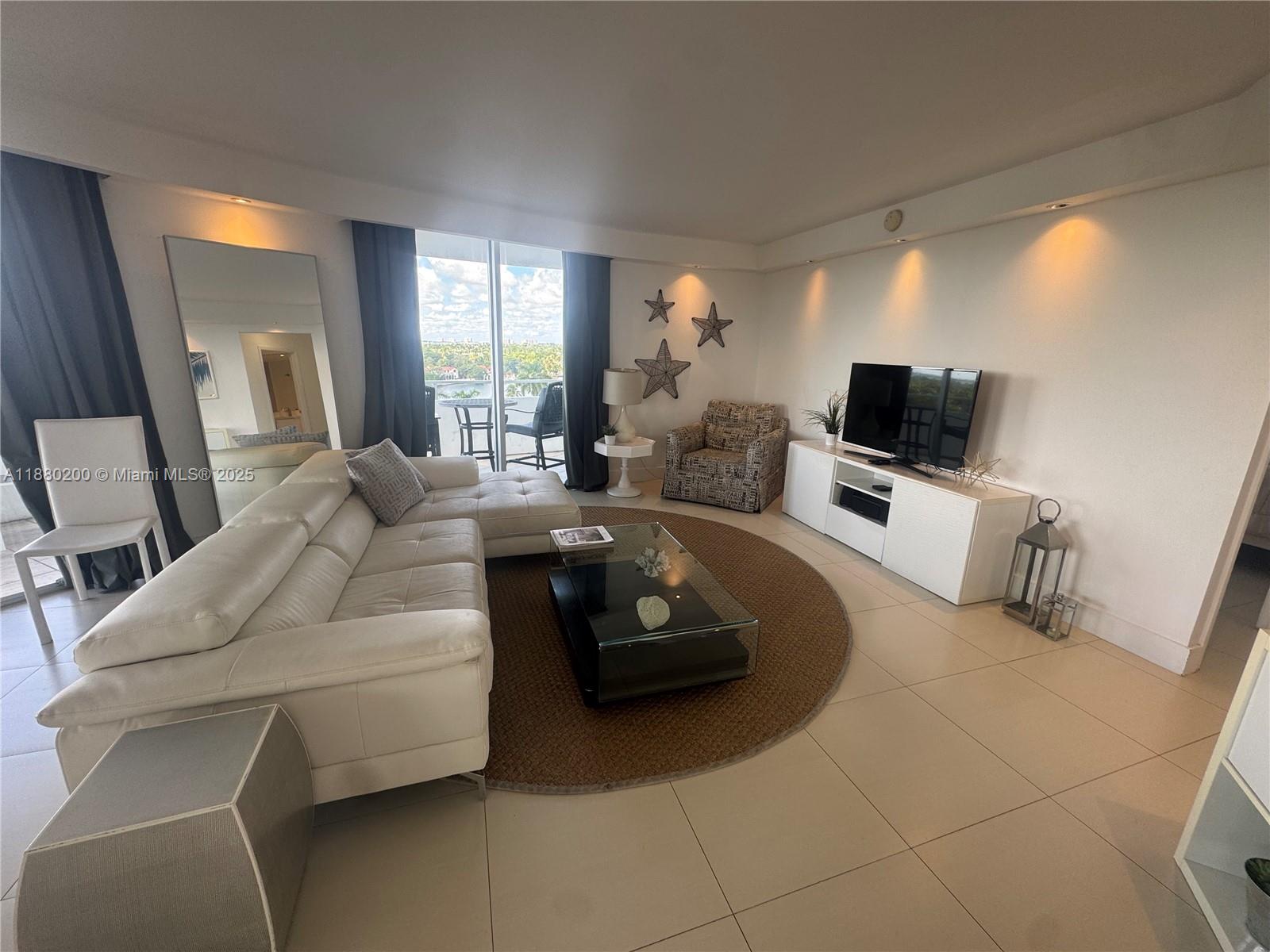 5151 Collins Avenue, Unit 923 Miami Beach, FL 33140 - Photo 6 of 32 a living room with furniture and a flat screen tv