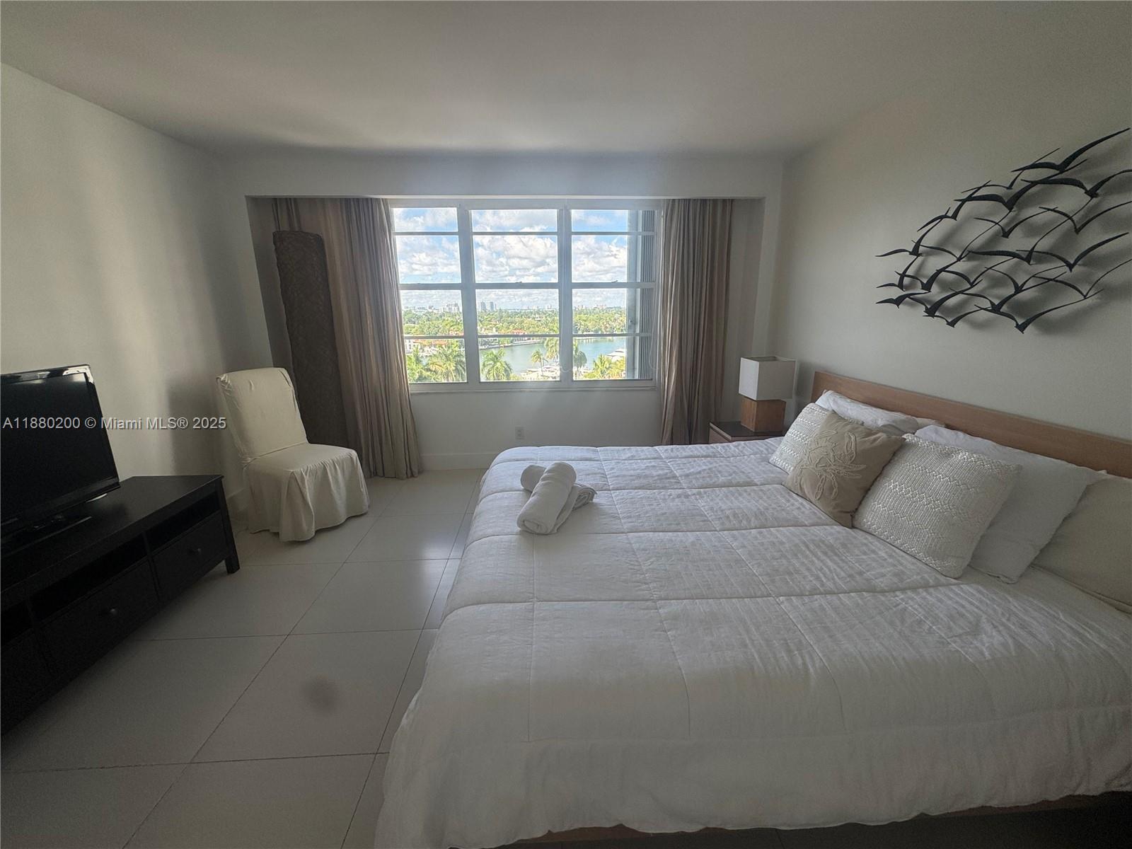 5151 Collins Avenue, Unit 923 Miami Beach, FL 33140 - Photo 8 of 32 a bed sitting in a bedroom next to a window with lamp