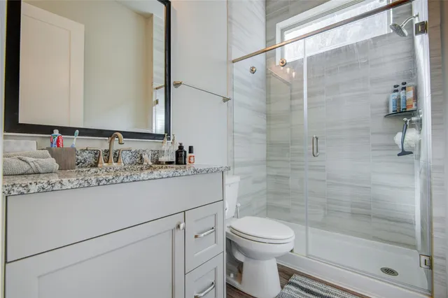 a bathroom with a granite countertop sink a toilet and shower