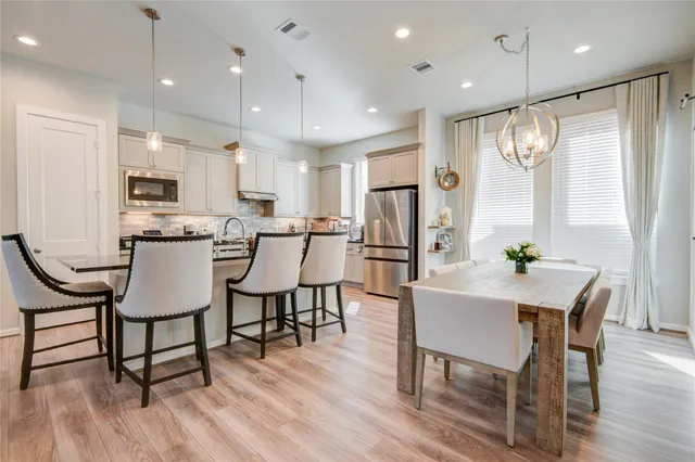 a kitchen with kitchen island granite countertop a table chairs sink and cabinets