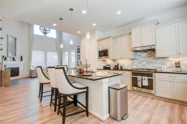 a kitchen with stainless steel appliances granite countertop a stove top oven a sink dishwasher a dining table and chairs with wooden floor