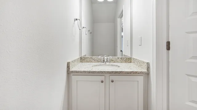 a bathroom with a granite countertop sink and a mirror